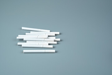 A lot of cigarettes are lying in a pile on a blue background. Side view, with copy space. Horizontal orientation.