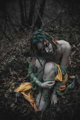 Fototapeta na wymiar dead girl in autumn foliage wearing green and yellow robes