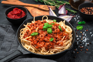 Classic Italian dish pasta bolognese on a black background. Top view, horizontal. Cooking concept.