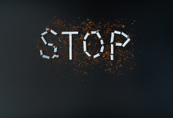 Anti-smoking, The word Stop is laid out of white cigarettes on a black background. Top view, with space to copy. The concept of the dangers of smoking.