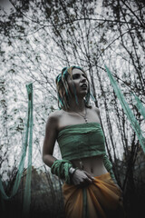 dead girl in autumn foliage wearing green and yellow robes