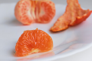 macro photo mandarin slices in a white plate close up several pieces of lie on the table background out of focus