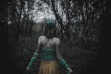 dead girl in autumn foliage wearing green and yellow robes