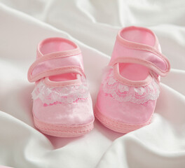 Baby girl shoes on white satin background,  pink cute soft footwear, baby shower concept