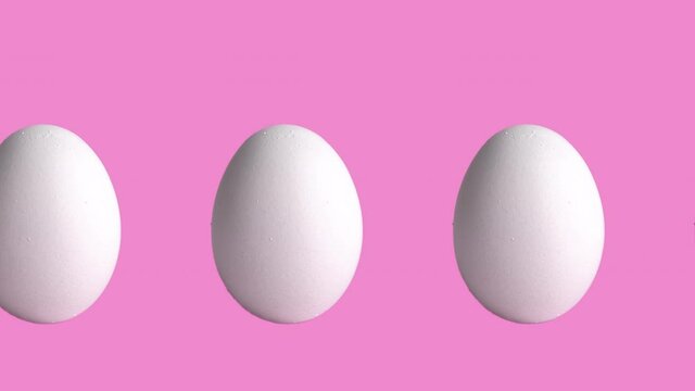 seamless looping animation with chicken raw eggs on rose and pink background, close-up. side view of farm products, easter concept with copy space