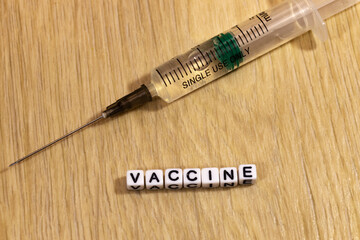 Inscription vaccine and syringe on a wooden background