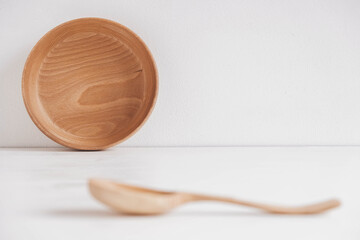 Empty wooden bowl and wooden spoon on a white table background. Copy, empty space for text