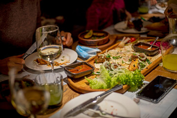 festive table with wine and mixed meat with salad and sauce on a chalkboard with lemonade for company, horizontal