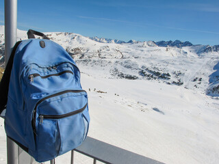 A blue backpack against the mountain's landscape and bright blue sky.  Travel content