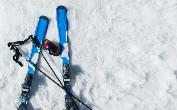Mountain skis, sunscreen mask and ski sticks on bright alpine snow. Travel, vacation, extremal sport content