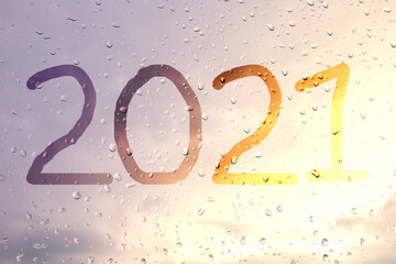 2021, the inscription on the glass with raindrops in the sunset light.