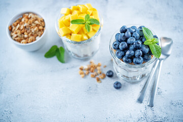 Mango  and blueberry Greek yogurt granola parfait in a glass