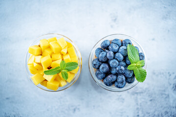 Mango  and blueberry Greek yogurt granola parfait in a glass