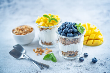Mango  and blueberry Greek yogurt granola parfait in a glass