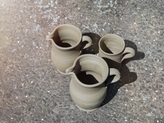 There are three clay jugs on the asphalt. View from above.