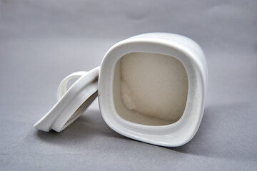close up of a white sugar-basin with sugar in it. 