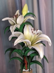artificial white lily flowers stand on a dark background