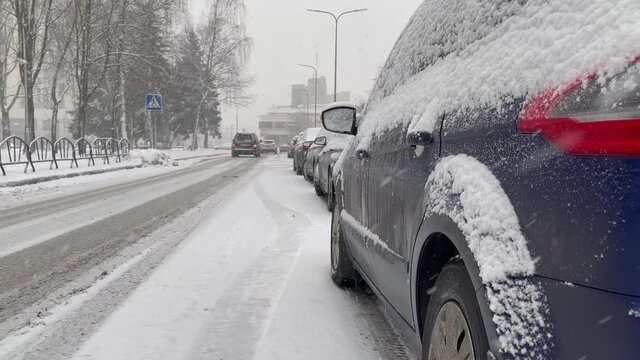Cars pass on a snowy city road