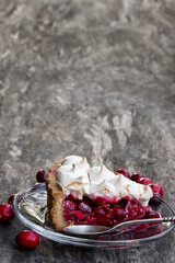 Meringue covered cranberry tart pie slice on wooden rustic background