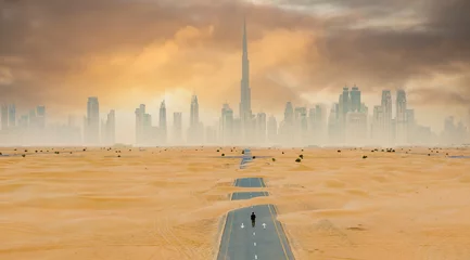 Fototapeten View from above, stunning aerial view of an unidentified person walking on a deserted road covered by sand dunes with the Dubai Skyline in the background. Dubai, United Arab Emirates. © Travel Wild