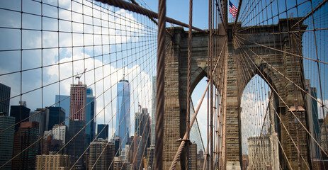 Brooklyn Bridge with modern buildings on the other side of the steel mesh.