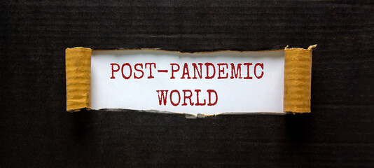 Post-pandemic world symbol. The words 'Post-pandemic world' appearing behind torn black paper. Beautiful black background, copy space. Medical and COVID-19 pandemic post-pandemic world concept.