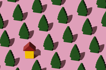 Modern forest pattern made with wooden trees and small yellow house against pastel pink background. Minimal concept