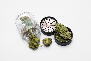medical marijuana flower buds near glass jar with grinder full of dry and crushed herb