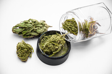 Fototapeta na wymiar medical marijuana flower buds near glass jar with grinder full of dry and crushed herb