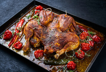 Traditional barbecue spatchcocked chicken al mattone chili with tomatoes and jalapeno served as close-up on an old rustic metal tray