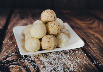 picture of handmade sweet dessert on a wooden background. - sweet balls wrapped in coconut and nuts
