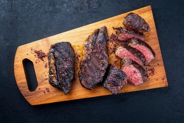 Modern style barbecue dry aged wagyu Brazilian picanha steaks from the sirloin cap of rump beef sliced and served as top view on a wooden design board with copy space