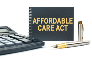 On a white background, there is a calculator, a pen and a black notebook with the inscription - AFFORDABLE CARE ACT