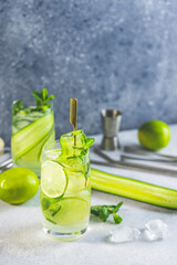 Detox cocktail with mint, cucumber and lime or mojito cocktail in highball glasses on a gray concrete stone surface background.
