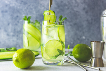 Detox cocktail with mint, cucumber and lime or mojito cocktail in highball glasses on a gray concrete stone surface background.