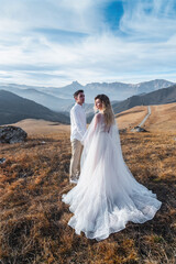 Fototapeta na wymiar A newlywed couple on the background of beautiful autumn mountains. The concept of holding a wedding in nature, love, family and relationships