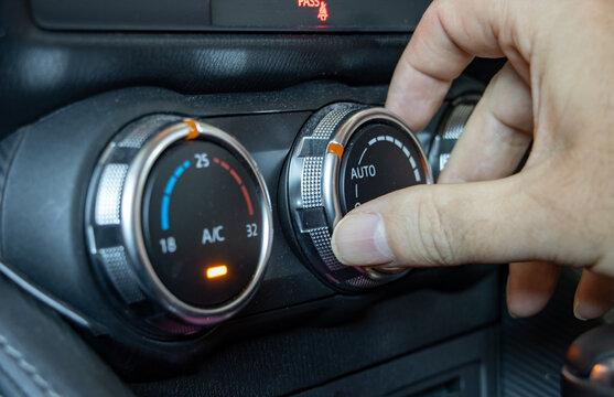 Using air condition in a car, close up. The hand manipulates the ventilation control knob inside the car.