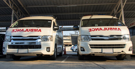 Front of ambulances standing in parking lot of hospital. A row cars of rescuers with red text ambulance on hood. © milkovasa