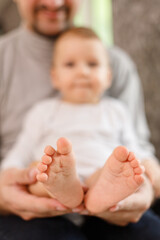 Father's hands carefully keeping baby's feet with tenderness