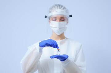 Doctor in medical gloves and a mask holds a vaccine in his hands