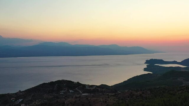 
Drone footage of a beautiful sunset at the Gerania mountain in Greece. The drone is facing the sea where the sun is setting, then pan to the right, to see the side of Gerania mountain. 4K
