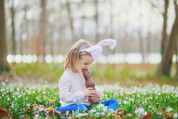 Fototapeta na wymiar Girl wearing bunny ears eating chocolate bunny