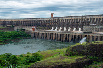 Naklejka premium Foz do Iguaçu, Brazil - January 26, 2021: Panoramic view of the Itaipu hydroelectric plant with water gushing through the floodgates. Clean and renewable energy.