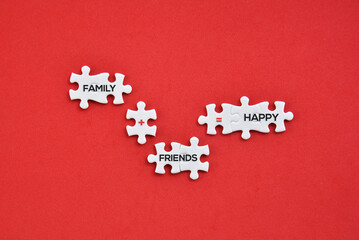 Obraz premium 'Family, friends, happy, plus and equal' word symbol on white puzzles with red background flat lay concept.