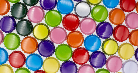 Different colored crown corks and caps lined up as a colored background in the colors blue, red, orange, gold and grey