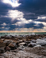 Lake Ontario dramatic clouds and waves on rocky shore from Kew Beach in Toronto's trendy Beaches neighbourhood verticle