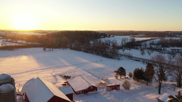 Rural scenery, Aerial view of American countryside landscape in winter. Farm, red barns from above. Sunny, sunset (sunrise), freezing cold weather, snow. Wisconsin, USA
