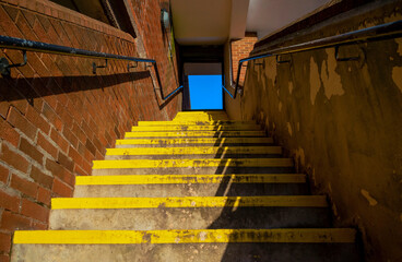 Yellow streaked stairs seen from the bottom up overlooking the blue sky at the top.