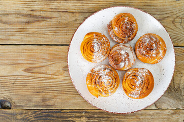 Plate of homemade cinnamon rolls on wooden table. Studio Photo