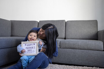 Mexican mother playing with son on carpet at home, mother's day